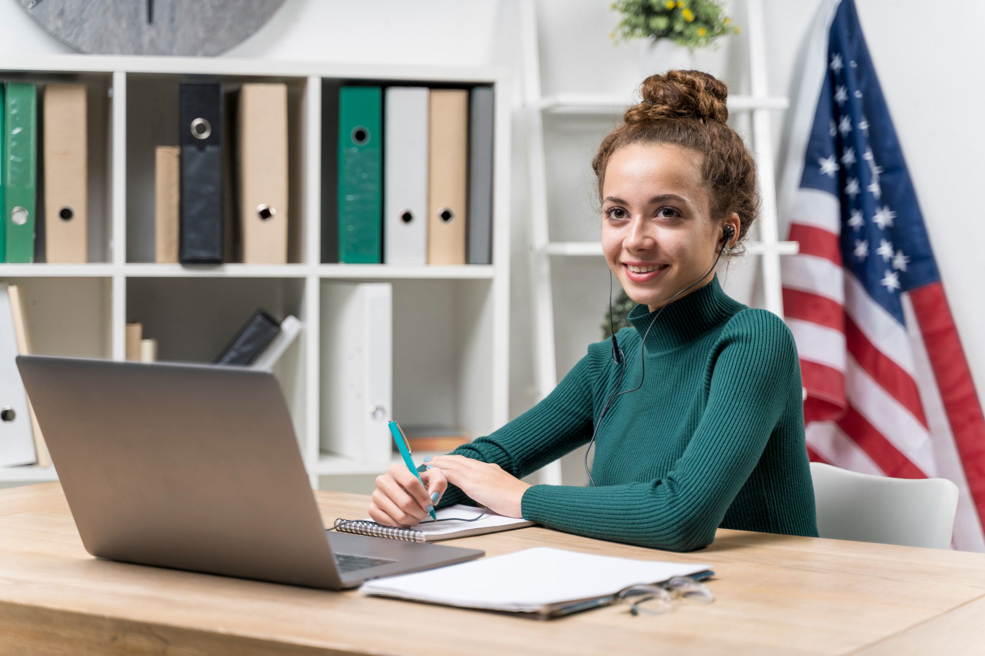 Interpreter taking notes at a laptop with a U.S. flag in the background